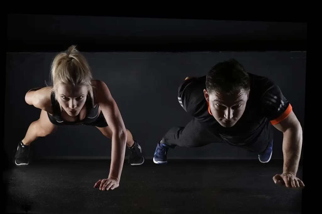 Two fitness enthusiasts performing one-arm push-ups in a gym, highlighting the debate on whether exercise is keeping people fat and questioning its true impact on weight loss